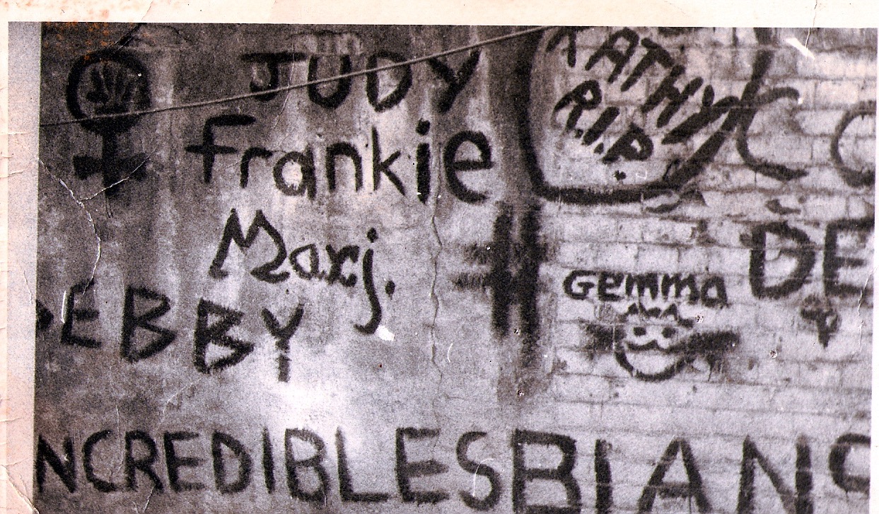 Photo of old brick wall; a garden in a squat in Vauxhall. Graffiti reads: 'Incrediblesbians.' Women's names painted on.